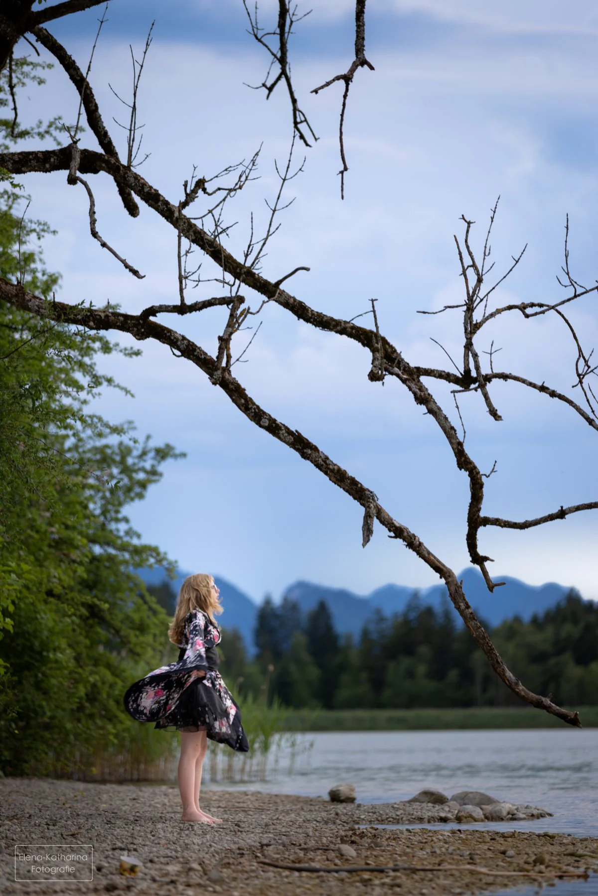 Junge Frau im Kimono unter einem hoch aufragenden Baum am See