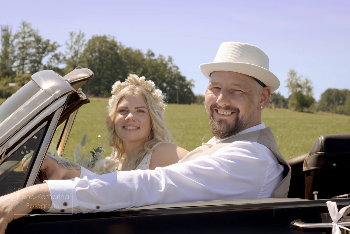 Glückliches Brautpaar im offenen Oldtimer