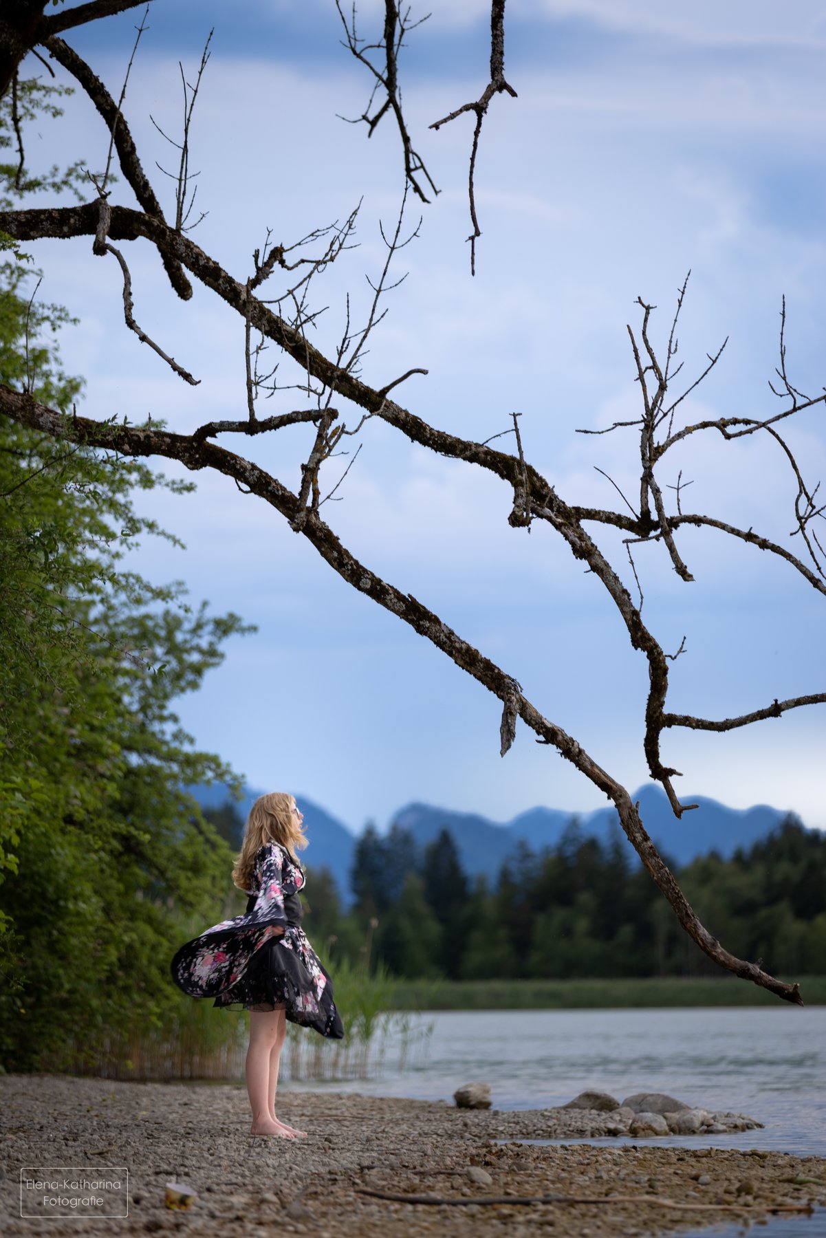 Junge Frau im Kimono unter einem hoch aufragenden Baum am See