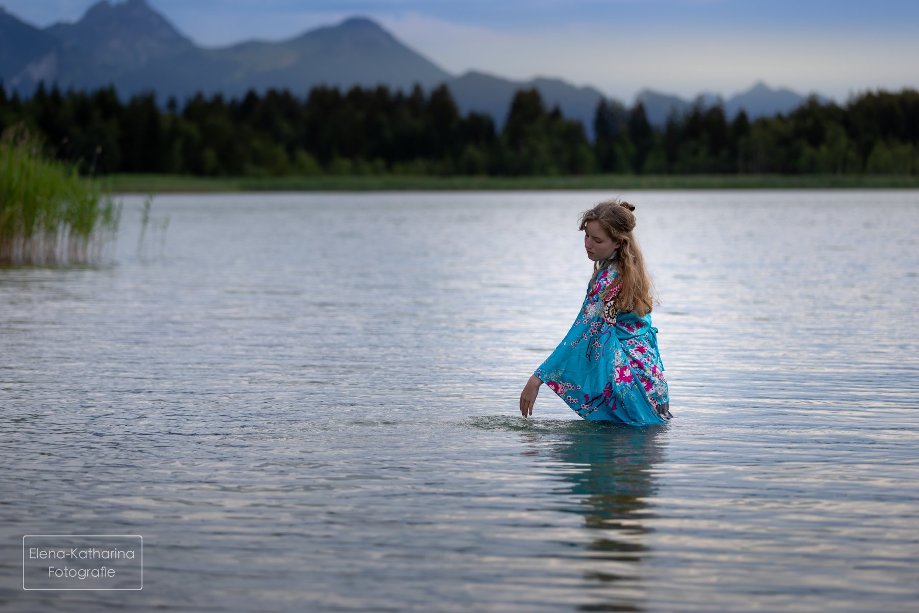 Künstlerisches Portrait im Wasser vor weiter Berglandschaft