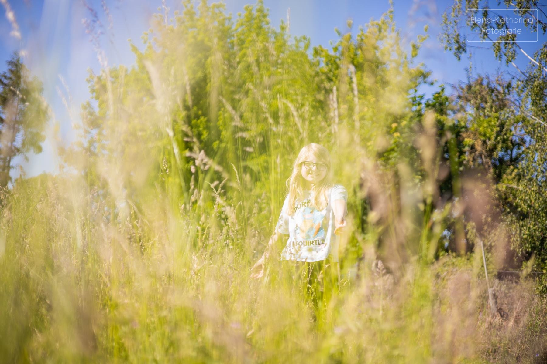 Kind bewegt sich frei durch eine hohe Wiese