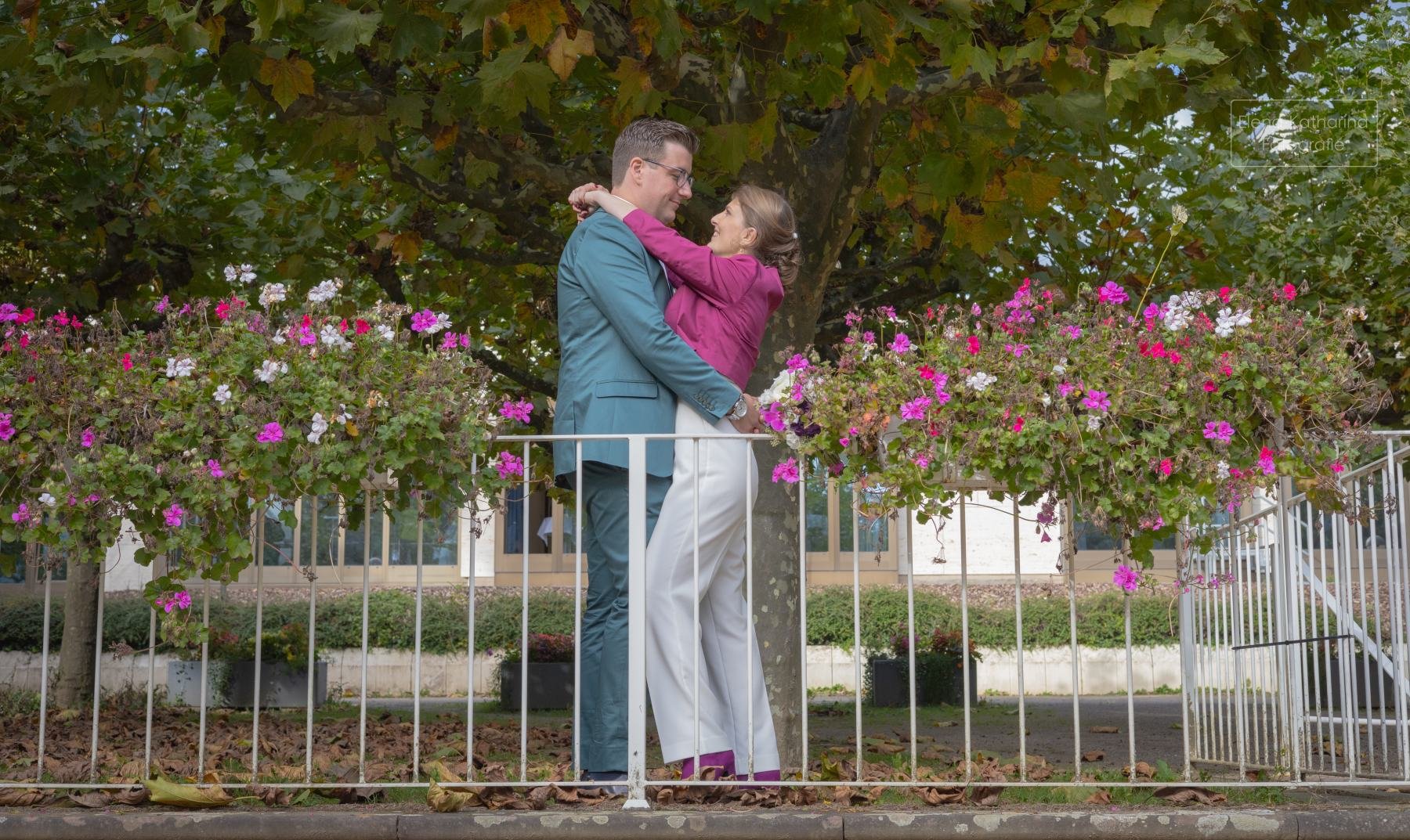 Brautpaar küsst sich vor blühenden Rosen