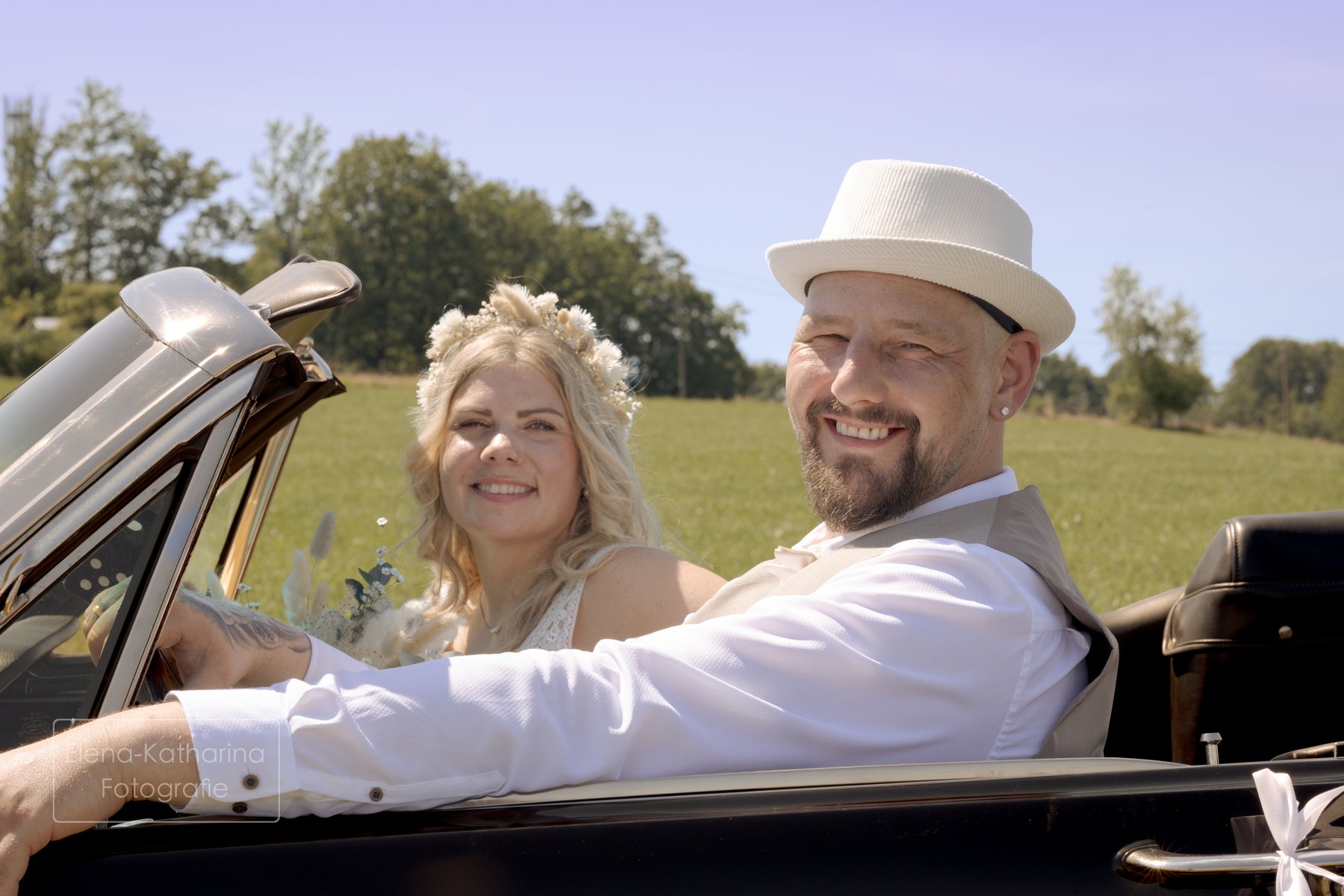 Glückliches Brautpaar im offenen Oldtimer
